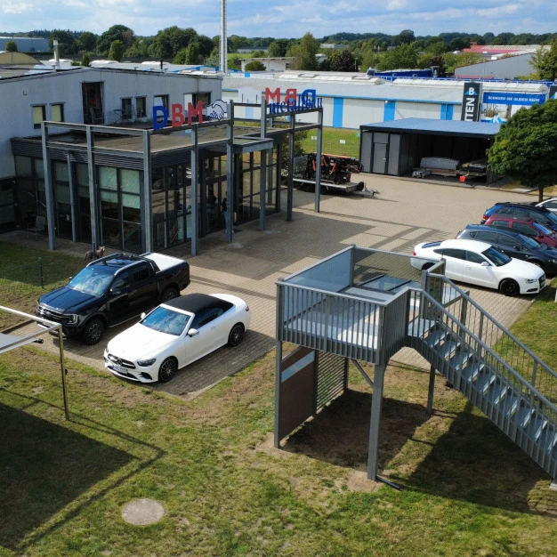 Ein Servicebereich mit geparkten Autos modernen Gebäuden und einer zugänglichen Metallrampe im Freien
