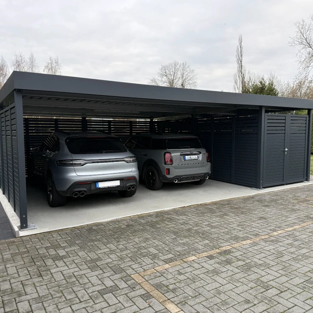 Modernes Carport mit zwei grauen SUVs auf einem gepflasterten Untergrund bei Tageslicht
