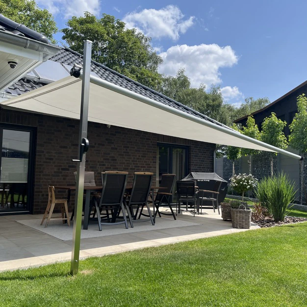 Moderne Hausterrasse mit Outdoor-Möbeln und Vordach eingebettet in eine grüne parkähnliche Umgebung