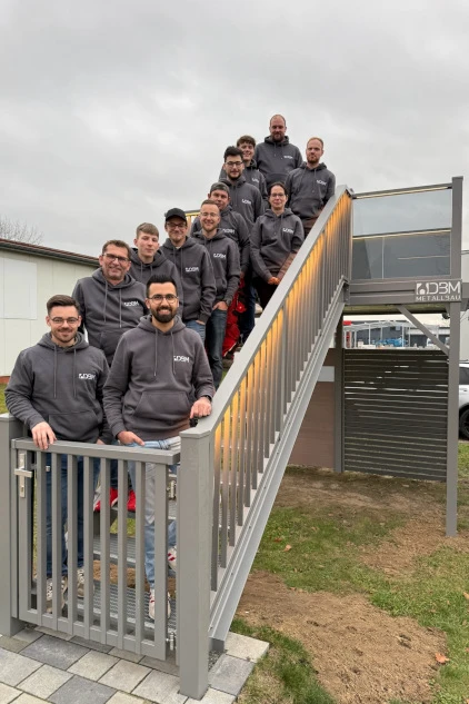 Gruppe von Männern in dunkler Kleidung lächelt auf einer modernen Metalltreppe