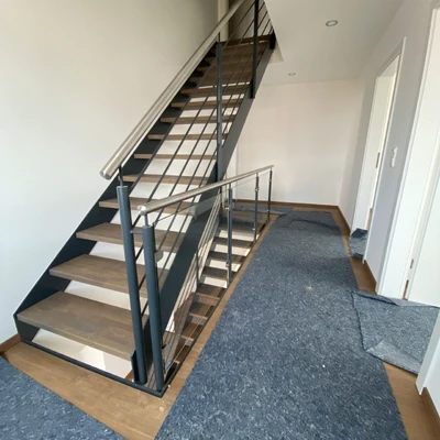 Moderne Treppe mit schwarzem Geländer und grauem Teppich