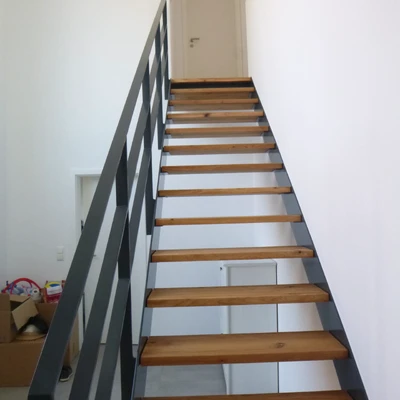 Moderne Holztreppe mit schwarzem Geländer in hellem Interieur