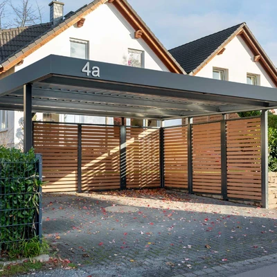 Überdachtes Carport mit Holzlatten und Haus im Hintergrund