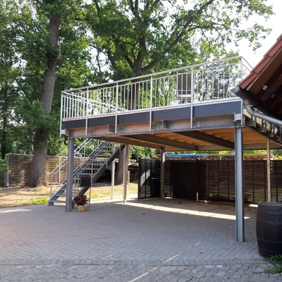 Hoch überdachte Plattform in Grünanlage mit Treppe und Sitzmöglichkeiten