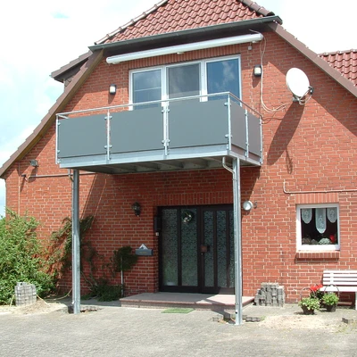 Redakierte Fassade mit Balkon und Eingangsbereich an Wohnhaus