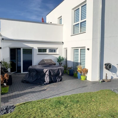 Neubau-Fassade mit gepflegter Terrasse und Garten