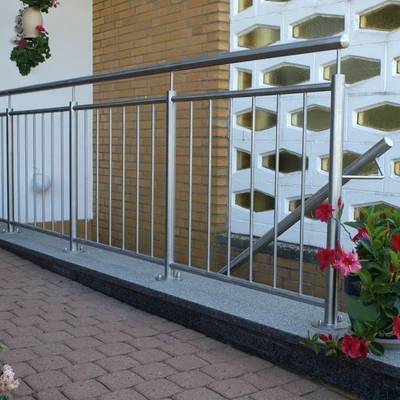 Metallgeländer vor weißer Fassade und Backsteinmauer