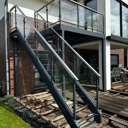 Moderne Außentreppe aus Metall und Glas über Schienen zu einem modernen Wohngebäude