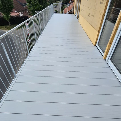 Modernes hellgraues Gehwegplateau begrenzt von Geländer links und gelber Wand rechts