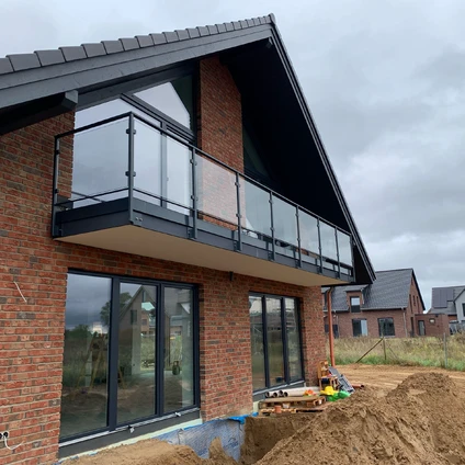Modernes Backsteingebäude im Bau mit Balkon großen Fenstern und Sandhaufen im Vordergrund