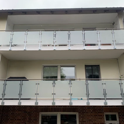 Moderne Fassade mit mehreren Stockwerken die durch Glas- und Metallgeländer abgeschlossen sind