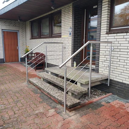 Barrierefreier Eingang mit Rampe und Metallgeländer vor hellen Backsteinfassaden