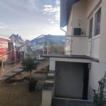 Moderne Fassade mit Glasgeländer Eingangsbereich und Blick auf die Straße und einen LKW