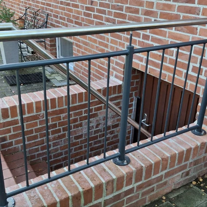 Schwarz-graue Metallgeländer vor einer Backsteinwand neben einer Außentreppe