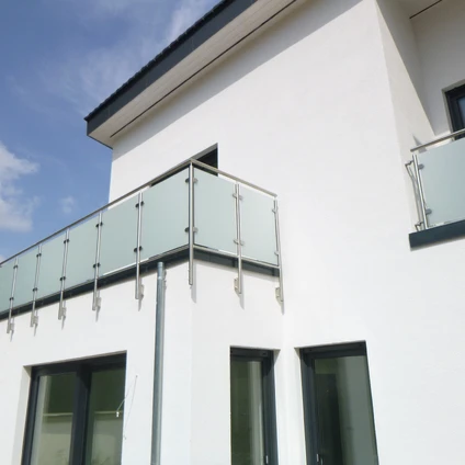 Weißes Wohnhaus mit modernem Glasbalkongeländer dunklen Fenstern und einer klaren Fassadengestaltung