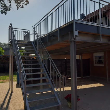 Metalltreppe zum Balkon eines modernen zweistöckigen Gebäudes bei Sonnenschein