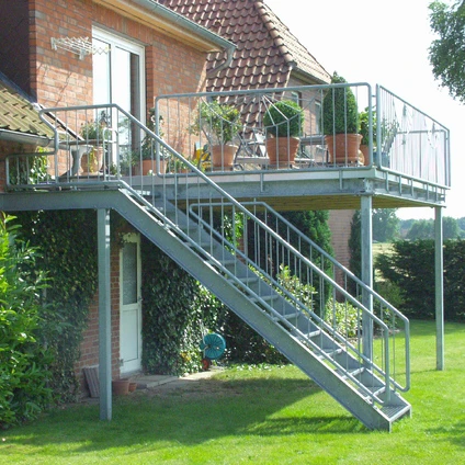 Moderne Metalltreppe und Balkon an einem Backsteinhaus im gepflegten Garten