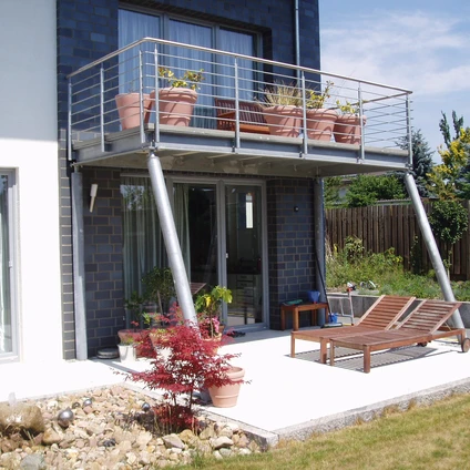 Modernes Haus mit Pflanzenbalkon und Patio Sonnenliegen draußen auf dem Vorplatz