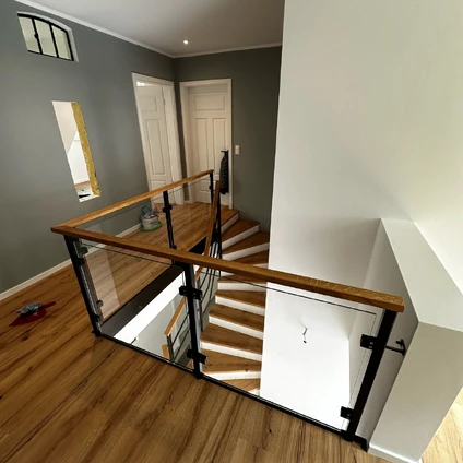 Modernes Geländer aus Glas und Holz an Treppenaufgang in schicker heller Wohnung