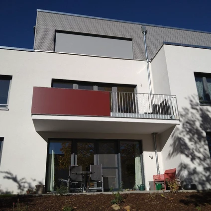 Modernes weißes Haus mit grauer Fassade roten Akzenten und breitem Balkon im modernen Stil