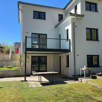 Modernes weißes Haus mit Balkon Gartenmöbeln und Sonnenschein im Freien