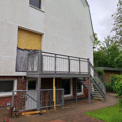 Modernes Wohnhaus mit neuem Metallbalkon und Zugangstreppe während einer Sanierung