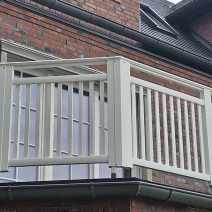 Ein Fenster mit modernem grauem Geländer vor einer roten Ziegelwand