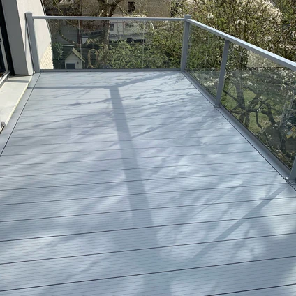 Heller Holzdeckboden mit Glasgeländer und ausgeprägten diagonalen Schattenmustern an sonnigem Tag