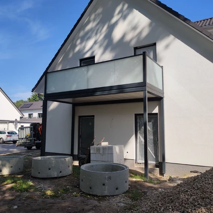 Modernes weißes Haus mit neuem Balkon und vor ihm runde Betonplatten