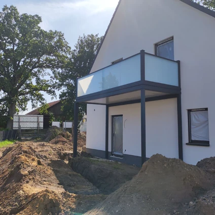 Modernes Haus mit Veranda vor Baustelle umgeben von Bäumen