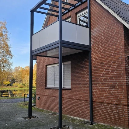 Moderne schwarze Balkonverglasung an einem Backsteinhaus mit Blick auf Herbstbäume
