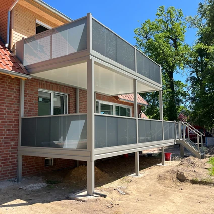 Eleganter neuer überdachter Balkon mit modernen Glasbrüstungen an einem Wohnhaus