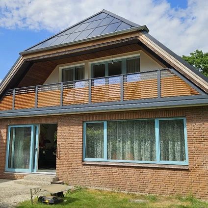 Modernes Ziegelhaus mit Solaranlage auf dem Dach Balkon und großen Fenstern