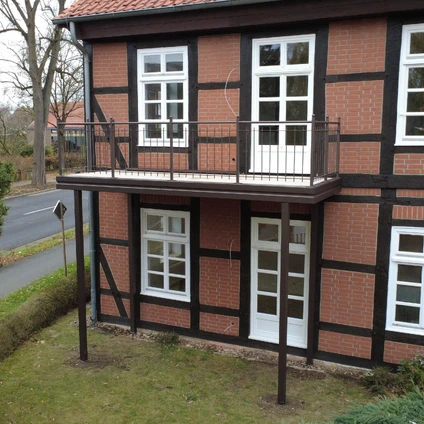 Zwei-Stockwerk-Fachwerkhaus mit roten Ziegeln weißem Balkon und großen Fenstern
