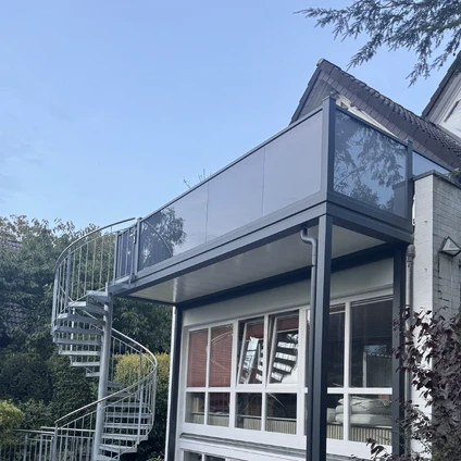 Moderne Hausanbau mit schwarzem Vordach großen Fenstern und spiralförmiger Außentreppe