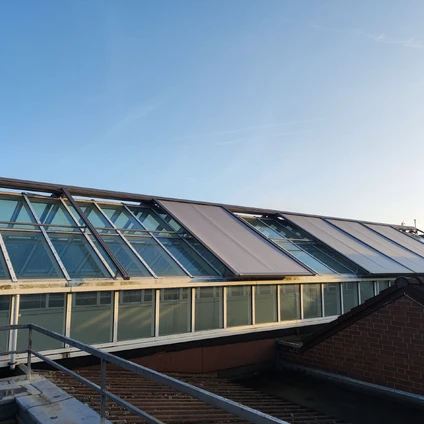 Moderne Architektur Glasdach Solarpaneele und rotes Ziegelmauerwerk unter blauem Himmel