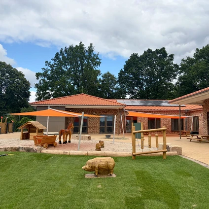 Großes Gebäude auf einem Bauernhof mit einem Schwein Spielgeräten und grüner Wiese