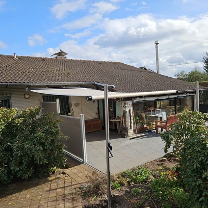 Ein Haus mit Terrakotta-Dach moderner Veranda und gepflasterter Terrasse unter blauem Himmel