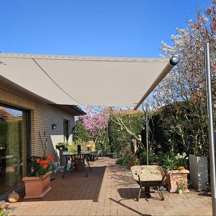 Sonniger Gartenpatio mit Überdachung Möbeln und blühenden Pinkbäumen an blauem Himmel
