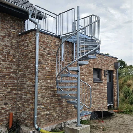 Geschwungene Metalltreppe an einem Backsteingebäude mit modernen Metallgeländern