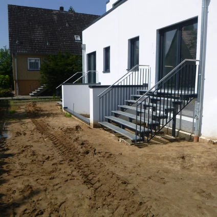 Weiße Fassade schwarze Treppe vor einem modernen Haus mit Schlamm-Vorplatz