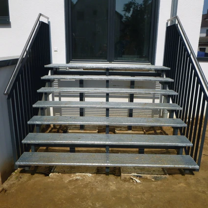 Metalltreppe im Außenbereich mit schwarzen Geländern vor einem Haus oder Gebäude