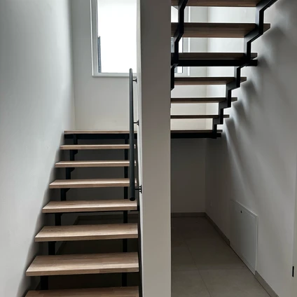 Zwei moderne Treppenhäuser mit Holzstufen und schwarzen Metallkonstruktionen in einem Innenraum