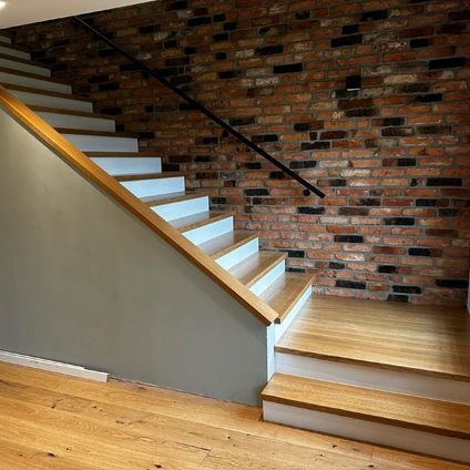 Moderne Holztreppe mit weißen Stufen vor einer dramatischen rustikalen roten Ziegelsteinwand