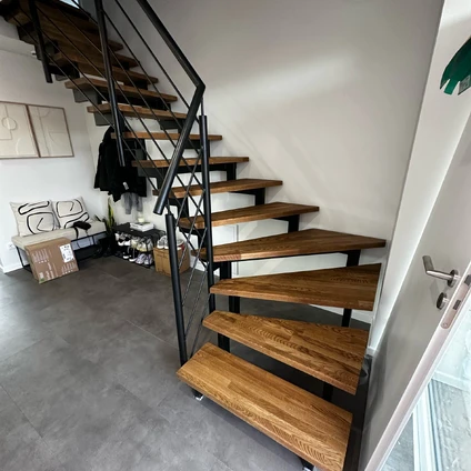 Moderne Treppe mit Holzstufen und schwarzem Metallgeländer in einem Wohnraum