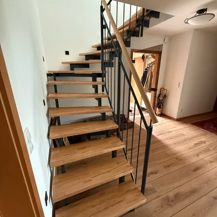 Moderne Holztreppe mit schwarzem Metallgeländer in einem hellen modernen Wohninterieur
