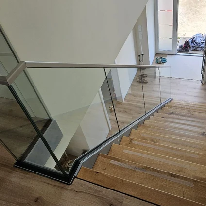 Modernes Treppenhaus mit Holztreppen Glasgeländer und Edelstahlhandlauf in einem Wohnraum