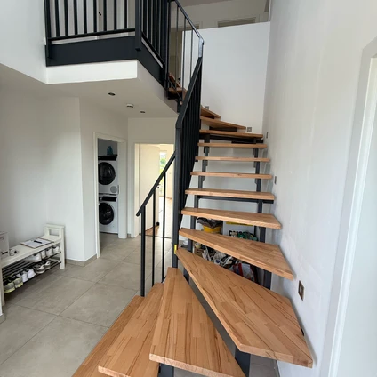 Moderne Holztreppe mit schwarzem Geländer in heller wohnlicher Innenarchitektur