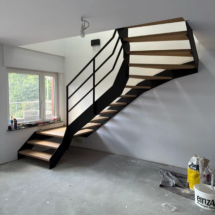 Minimalist black metal staircase with light wood treads in a modern empty interior setting