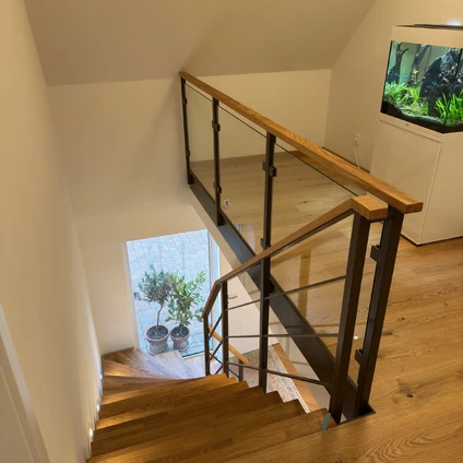 Moderne Holztreppe mit Glasgeländer und Holzhandlauf in einem Wohnraum